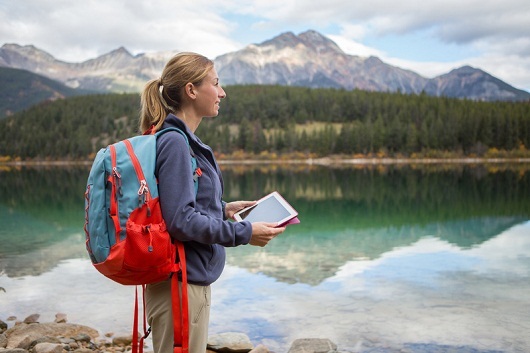 Young woman hiking by the lake using digital map