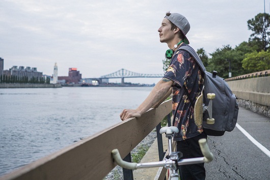 Young man with bicycle enjoying view by river, Le Plateau, Montreal, Quebec, Canada