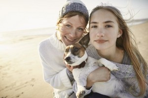 Mother and daughter with little dog on the beach