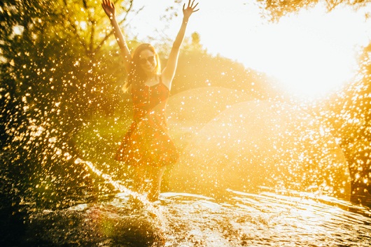 Young woman in a river playing with water, on a sunny day. Summer fun time.