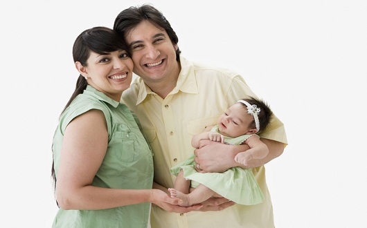 Proud Hispanic couple holding newborn baby