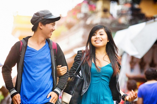 Happy young Indonesian woman shows her male friend Ubud with a big smile.