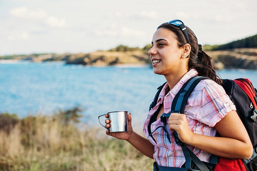 Smiling woman tourist in the mountain near the sea contemplating the nature scene, and copy space