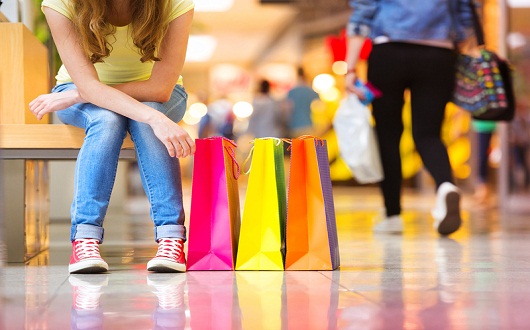 Shopping time, closeup of teenage girl's legs with shopping bags at shopping mall