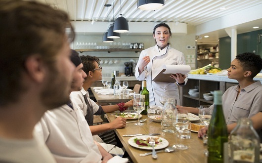 Head chef speaking to restaurant staff family meal